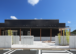 コンクリート外壁の奥にある黒い壁の家の写真