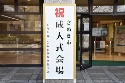 「祝 さぬき市成人式会場」と書かれた看板が建物入口に置かれた写真