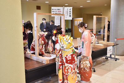 振り袖姿の女性たちが台の上の用紙に記入している写真