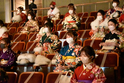 振り袖姿の女性が傾斜のついた客席に座っている写真