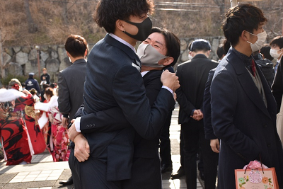 スーツを着用した男性2人が抱き合っている写真