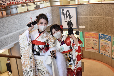 振り袖姿の女性2人が手をつなぎ、ピースサインしている写真