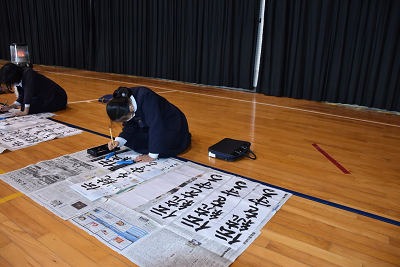 児童が筆を持って文字を書いている写真