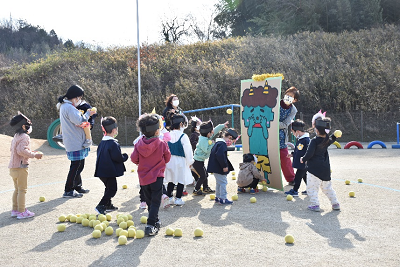 泣いている緑の鬼のイラストが書かれた段ボールにボールを投げる児童たちの写真