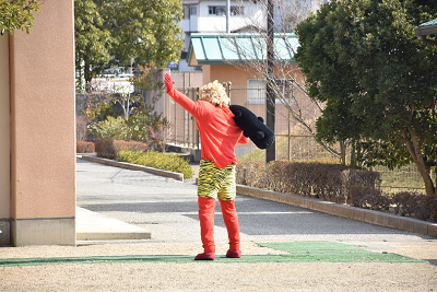 赤い鬼の仮装をした人が片手をあげ去っていく後ろ姿の写真