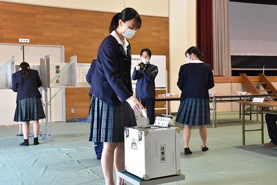 投票箱に用紙を入れている女子生徒の写真
