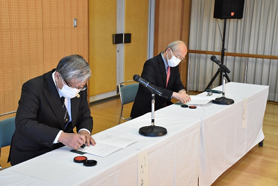 男性2人が書類にハンコを押している写真