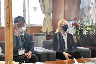 座って話す金髪女性の写真