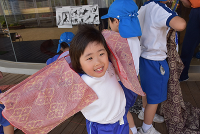 着物の生地を腕につけている園児の写真