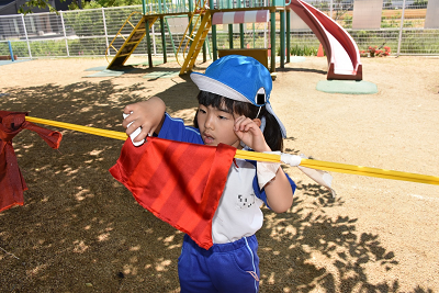 生地を紐にホッチキスでとめる園児の写真