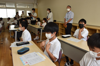 席に座り、両手の人差し指を自分に向けている児童の写真