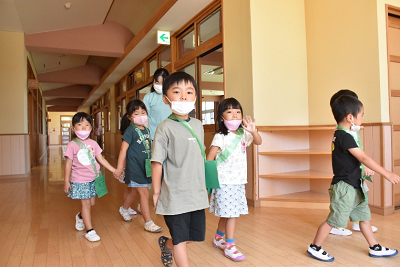 マスクを着用した児童たちが手をつないで歩いている写真