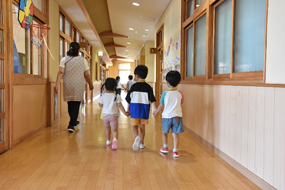 手を繋いで廊下を歩く園児たちの後ろ姿の写真