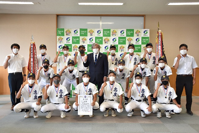 野球のユニフォームを着た人やスーツ姿の人たちが優勝旗や賞状を持ちガッツポーズを決めている写真