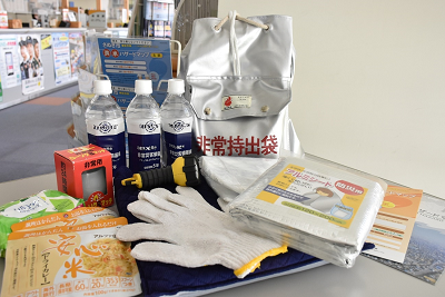 非常用持出袋や常備水などの防災グッズが机の上に置かれている写真