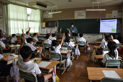 授業を受けている児童たちが手を挙げている写真