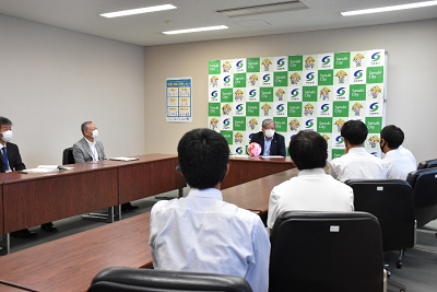 白いワイシャツを着た人たちがスーツ姿の男性を見ている写真