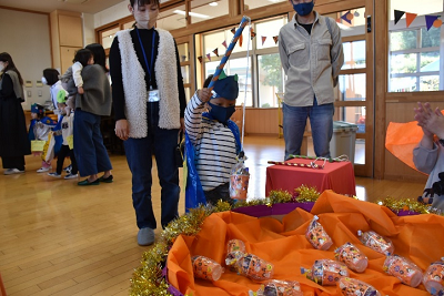 バーレル容器に入って包装されたお菓子を手作りの青い釣り竿で釣っている園児の写真