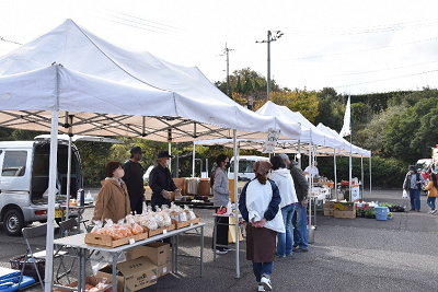 白いテントで売り物の後ろに立っている人の写真