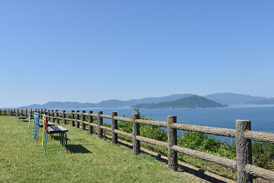 柵が立っている芝生の向こうに海が見える写真