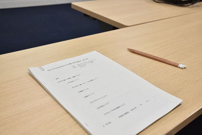 机にクリップ留めされた資料と鉛筆が置かれている写真