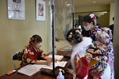 振り袖姿の女性が机越しに向き合い説明を受けている写真