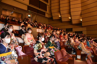 振り袖やスーツを着用した男女が観客席に座っている写真