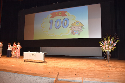 ステージ上のスクリーンに「100」と映し出されている写真