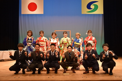 2列に並んだ男女が右手で「2」左手で「0」を作っている写真