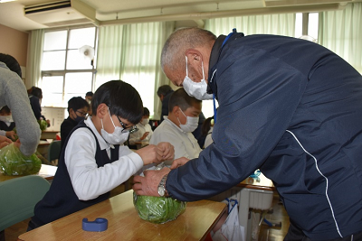 男性と一緒にレタスを包装する児童の写真