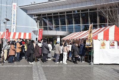 赤白の縞模様のテントに並ぶ人々の写真