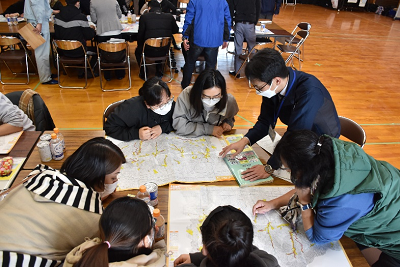 机にハザードマップを広げ、囲んで見ている女性たちの写真