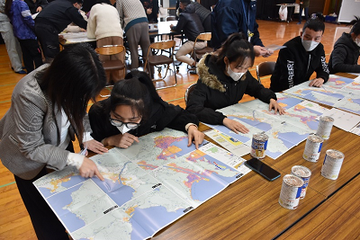 机にハザードマップを広げ、指さしながら確認する人たちの写真