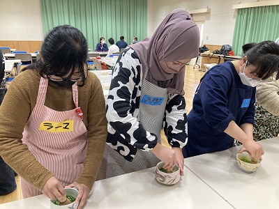 3人の女性が立って並び、抹茶を立てている写真