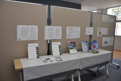 長机の後ろに設置された衝立に立てかけるように並べられた資料の写真