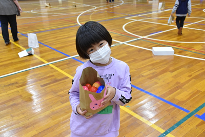 ボールが入ったウサギのイラストが書かれている紙袋を持つ女子児童の写真