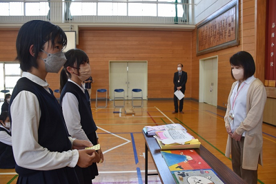 長机越しに話している児童2人と女性の写真