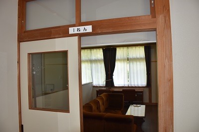 茶色のソファが置かれた部屋の扉が開いている写真