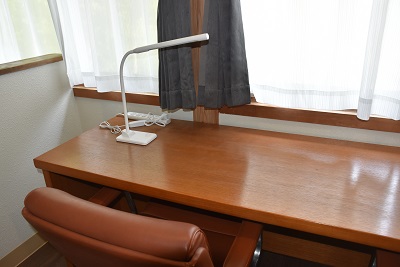 デスクライトが置かれた木製の机の写真