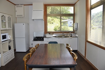 冷蔵庫やレンジ、6名掛けの机が設置されたキッチンの写真