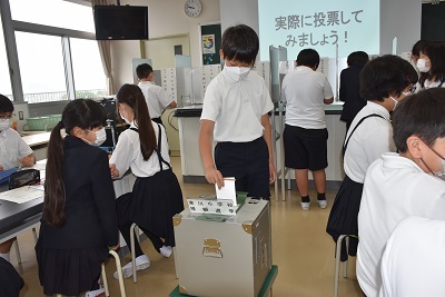 投票箱に用紙を入れる男子児童の写真