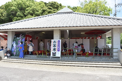 「お茶席」と書かれた看板が立つ瓦屋根の東屋の写真