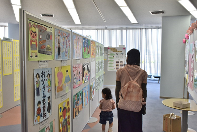 パネルに貼られたポスターを見る親子の写真