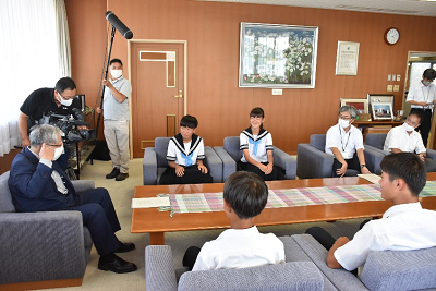 男性と話している生徒たちにマイクを向けている人の写真