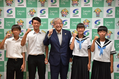 男性と生徒4人が並んでガッツポーズをしている写真