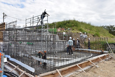 建物の基礎にヘルメットを着用した人たちが集まっている写真