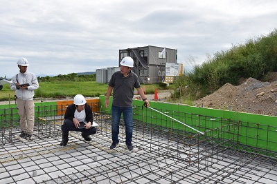 ヘルメットを着用した人たちが建物の基礎を確認している写真