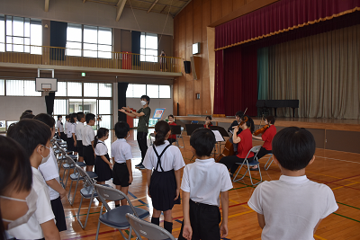 指揮に合わせて合唱する児童達の写真