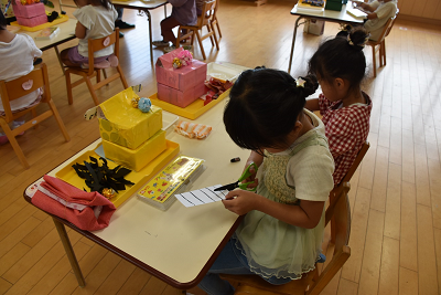 数本の黒い線が引かれた白画用紙を切る園児の写真