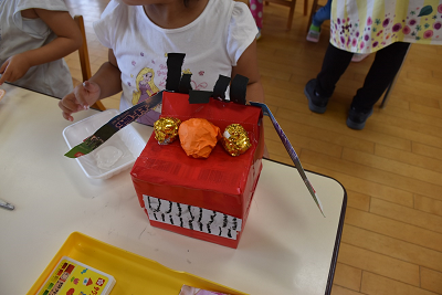 金色の目、オレンジ色の鼻をした手づくりの赤い獅子舞の頭の写真